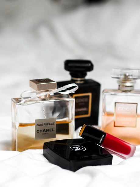Luxuriöse Chanel-Düfte mit eleganten Parfumflakons, begleitet von rotem Lippenstift und einem edlen Kosmetik-Compact. Stilvolle Beauty-Produkte für einen exklusiven Look.